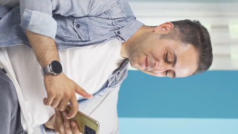 Vertical-video-of-The-man-looking-at-the-phone-is-happy.